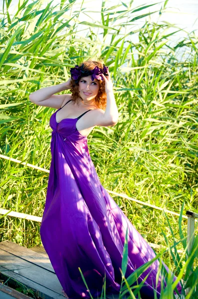 Красивая девушка с вьющимися волосами летит в фиолетовом платье — стоковое фото