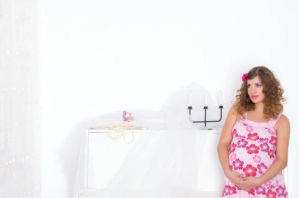Mujer embarazada en vestido rosa en la habitación — Foto de Stock