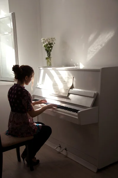 Silueta dívky, která hraje bílý klavír — Stock fotografie