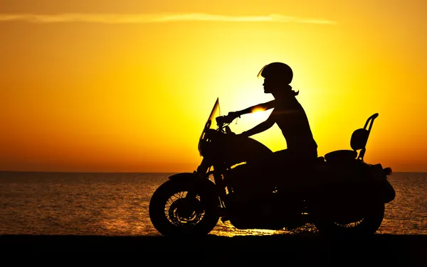 Mulher motociclista sobre o pôr do sol — Fotografia de Stock