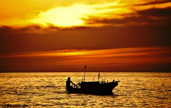 Fisherman on the boat over dramatic sunset — Stock Photo, Image