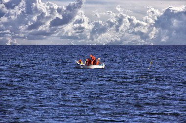 Fishermen fishing in the sea in a small boat clipart