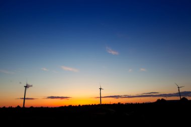 Blue orange sunset with electric windmills clipart