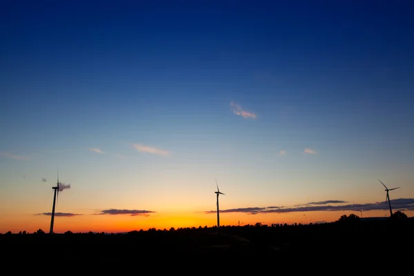 Pôr-do-sol laranja azul com moinhos de vento elétricos — Fotografia de Stock
