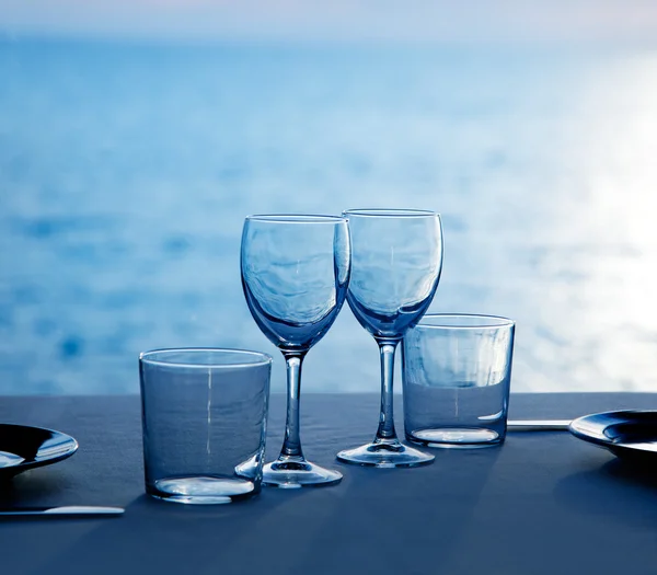 Glass dish cups and glasses on blue sea — Stock Photo, Image