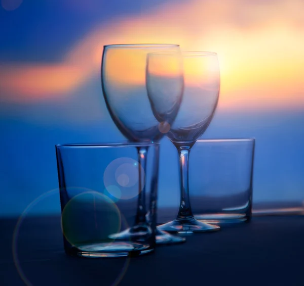 Prato de copos e copos de cristal no pôr do sol do mar — Fotografia de Stock