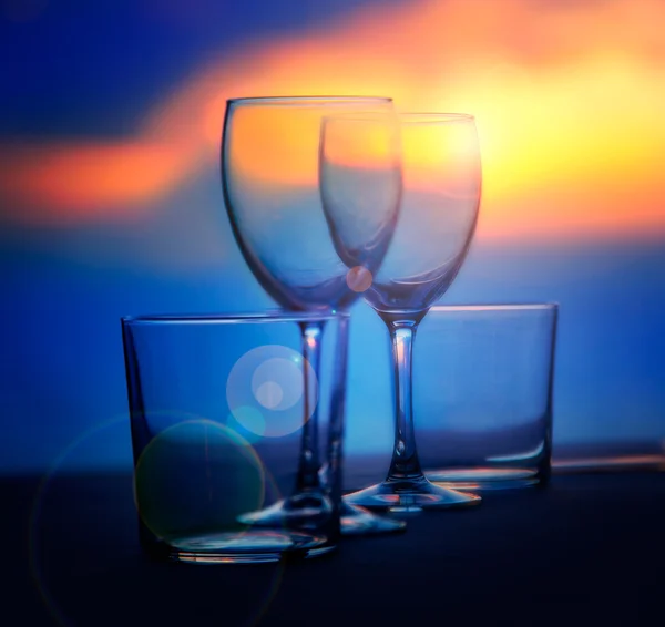 Plato de copas y vasos de cristal en el atardecer del mar — Foto de Stock