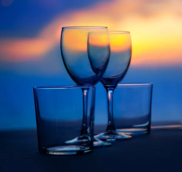 Schotel van kopjes en kristallen glazen op zee zonsondergang — Stockfoto