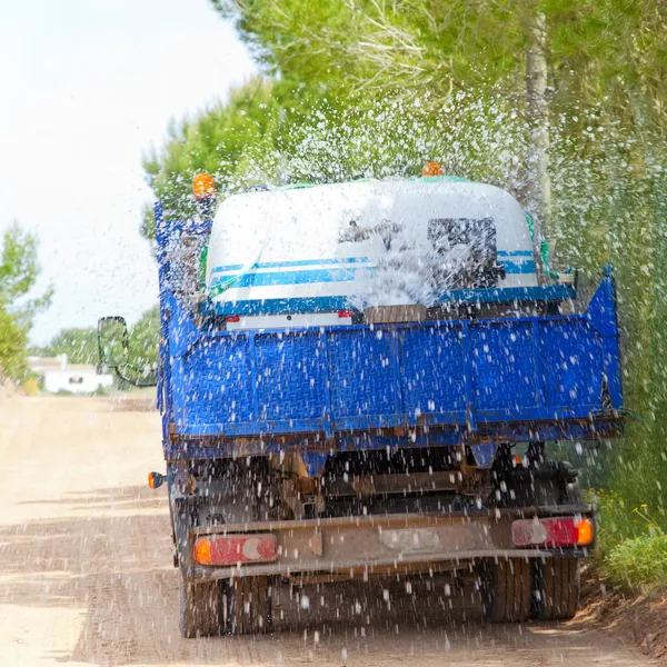 Lorry truck spreading sprinkle water on sand road — Stock Photo, Image