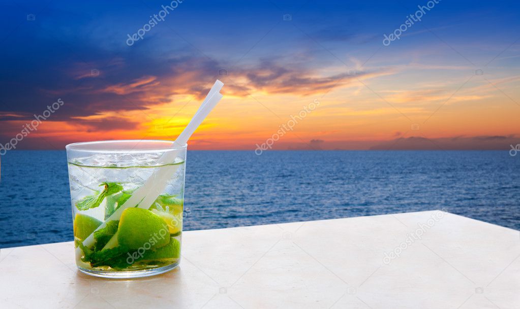 Mojito cocktail on a sunset beach golden sky