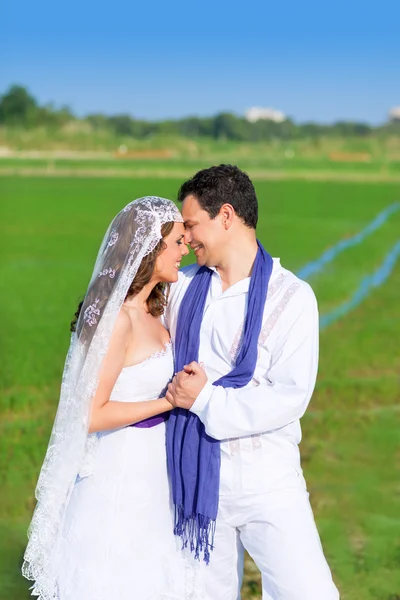 Par i bröllop dag kram på grön äng — Stockfoto