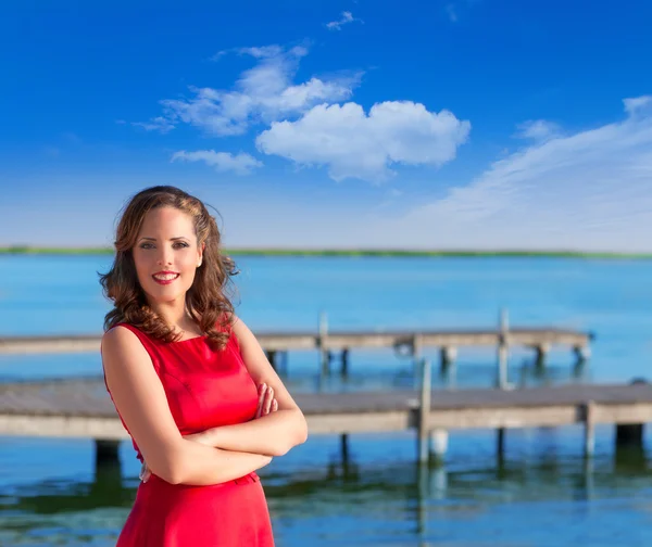 Bruneta žena šaty v červené usmívající se uvolněně na jezeře — Stock fotografie