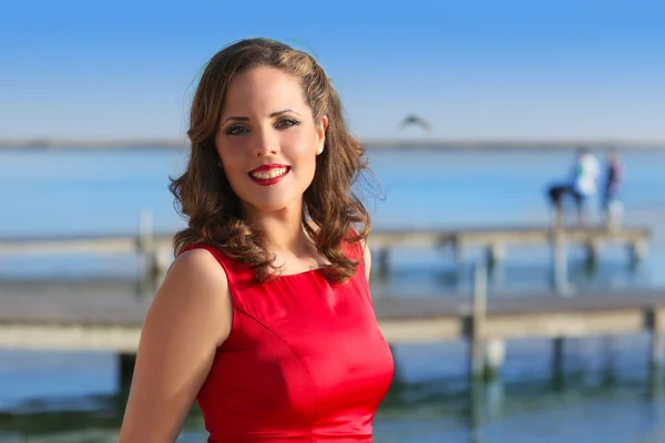 Брюнетка женщина платье в красном улыбается расслабленной на озере — стоковое фото