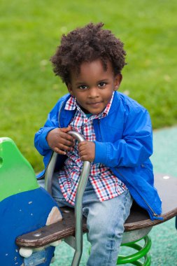 Outdoor portrait of a black baby playing at playground clipart