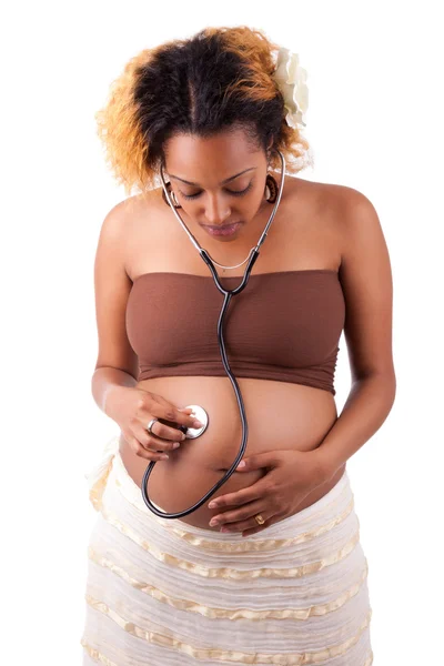 Mujer africana embarazada escuchando a su bebé con un estetoscopio — Foto de Stock