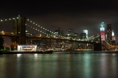 Manhattan skyline by night from Brooklyn bridge park clipart