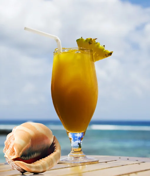 Cocktail de frutas tropicais e concha do mar com oceano no fundo — Fotografia de Stock
