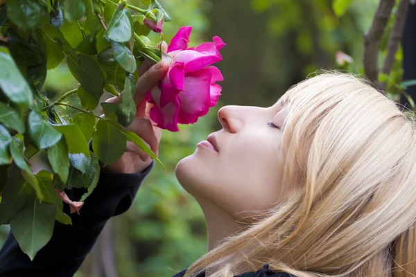 Lady smelling a rose ih a baroque park — Stock Photo, Image