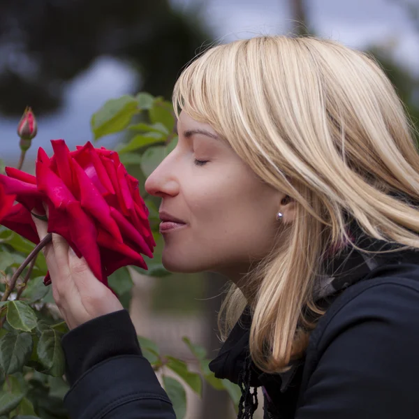Lady smelling a rose ih a baroque park — Stock Photo, Image