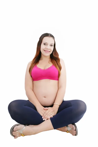Беременная женщина сидит на полу и улыбается. — стоковое фото