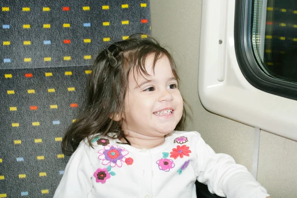 Милая маленькая девочка смотрит в окно в движущемся поезде — стоковое фото