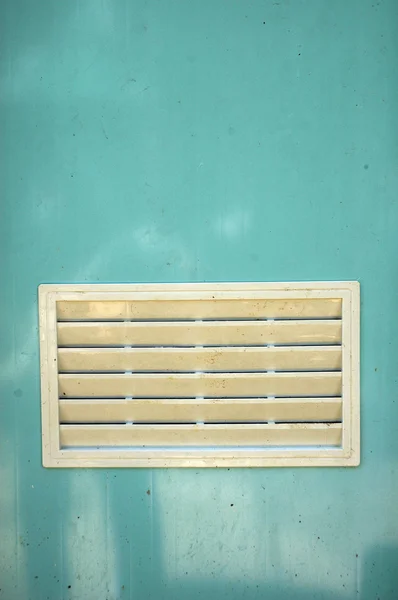 Špinavá bílá větrací okno na světle modré plastové dveře — Stock fotografie