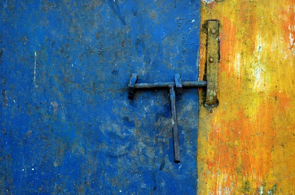 Feche a porta na parede azul e amarela desbotada — Fotografia de Stock