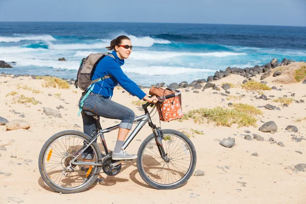 Kadın binicilik bisiklet bir plajda — Stok fotoğraf
