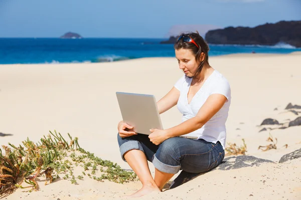 Žena na pláži s přenosným počítačem — Stock fotografie
