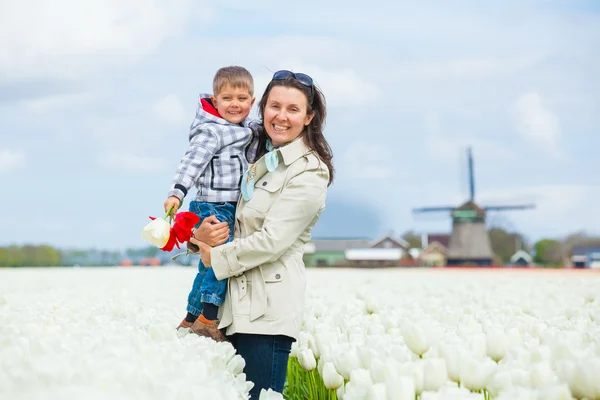 Chłopiec z matką w polu fioletowe tulipany — Zdjęcie stockowe