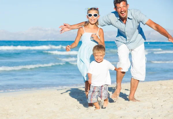Счастливая семья на тропическом пляже — стоковое фото