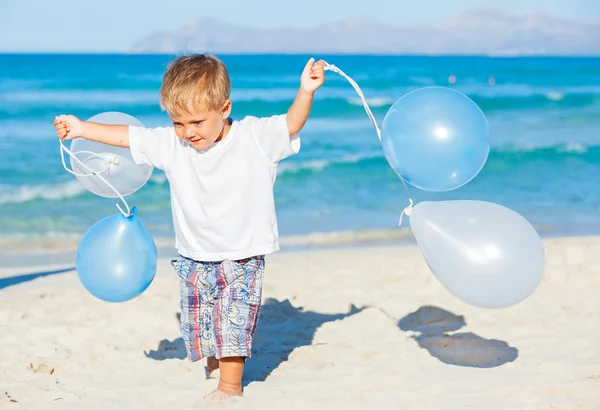 Jongen speelt met ballons op het strand — Stockfoto