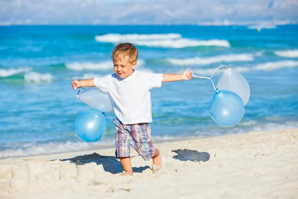 Pojke leker med ballonger på stranden — Stockfoto