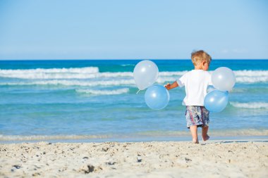 Boy plays with ballons on the beach clipart