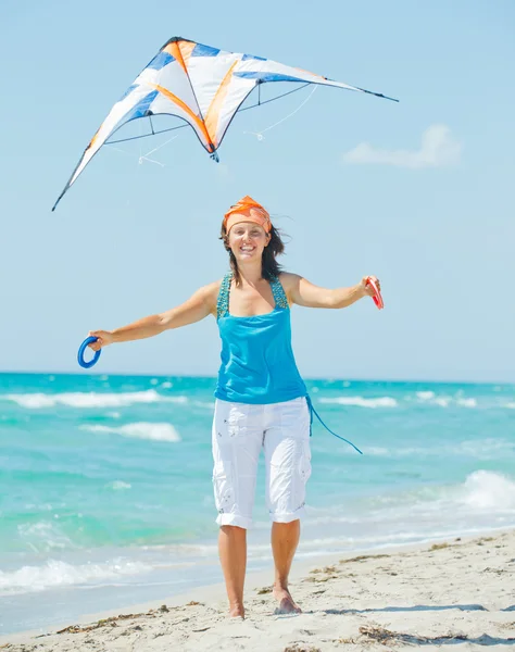 Mulher na praia brincando com um papagaio colorido — Fotografia de Stock