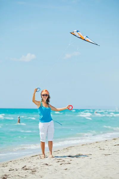 Mulher na praia brincando com um papagaio colorido — Fotografia de Stock