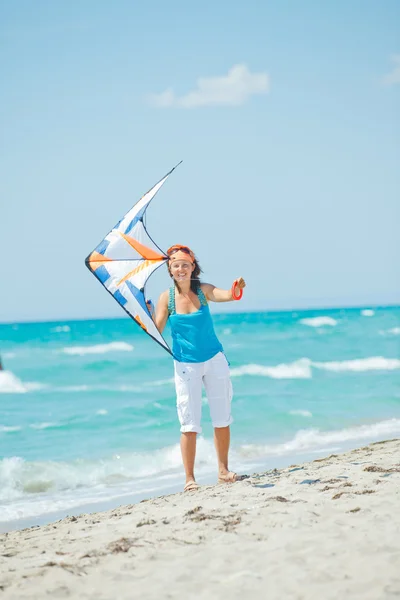 stock image Woman on beach playing with a colorful kite