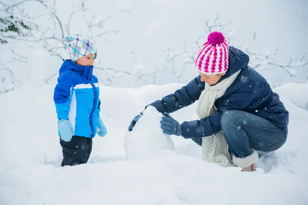 Garçon d'hiver lançant boule de neige avec mère — Photo
