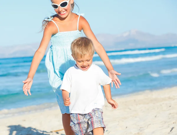 Chica joven y niño jugando felizmente en la playa bonita —  Fotos de Stock