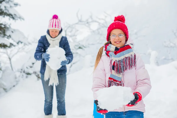 Chica de invierno lanzando bolas de nieve con madre — Stockfoto
