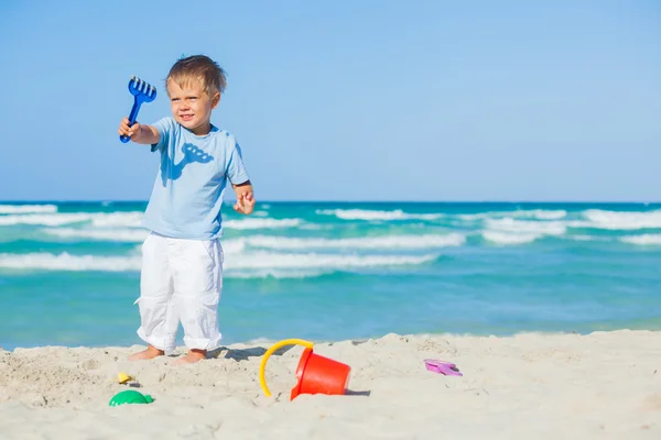 Мальчик с игрушками на пляже — стоковое фото