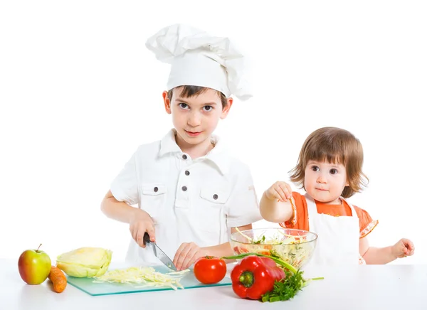 Twee lachende kinderen die salade mixen — Stockfoto