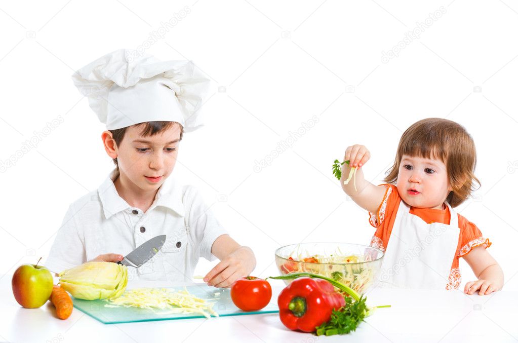 Two smiling kids mixing salad