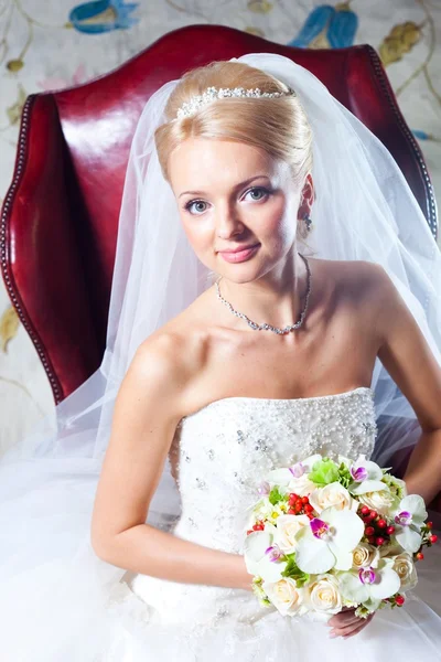 Bela noiva sentada em poltrona vermelha — Fotografia de Stock