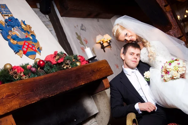 Schöner Bräutigam und Braut am Kamin sitzend — Stockfoto