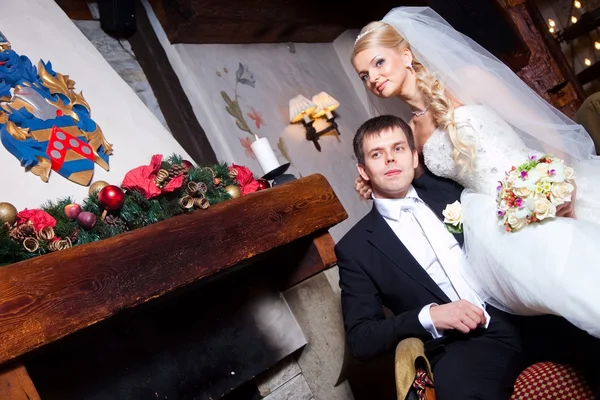 Красивый жених и невеста сидят у камина — стоковое фото