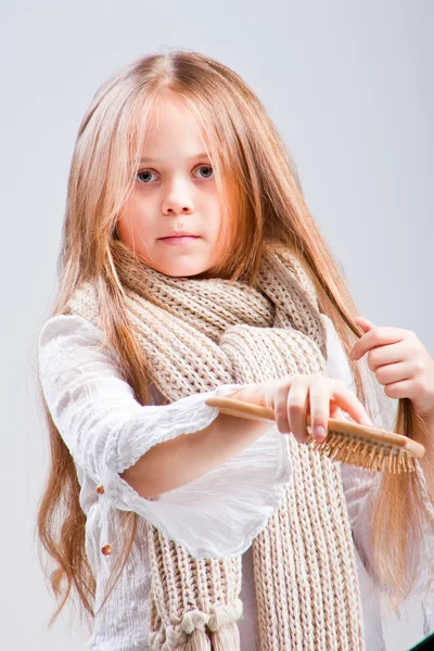 Ragazza carina pettinando lunghi capelli biondi — Foto Stock