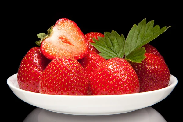 Platillo blanco con fresa roja sobre fondo negro — Foto de Stock