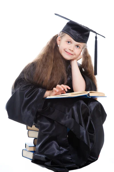 Chica en gorra académica negro y vestido de leer gran libro azul — Foto de Stock
