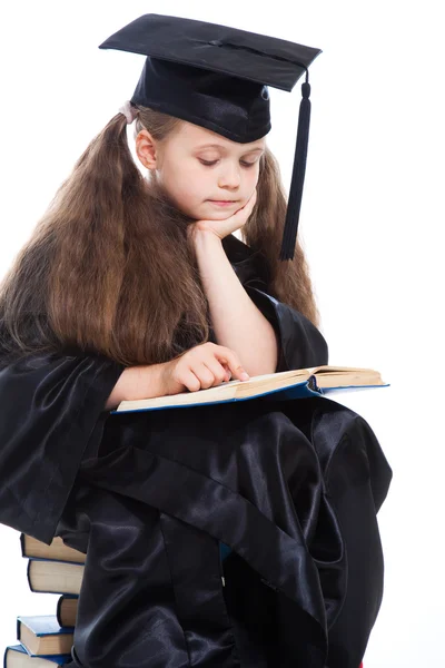 Chica en gorra académica negro y vestido de leer gran libro azul —  Fotos de Stock